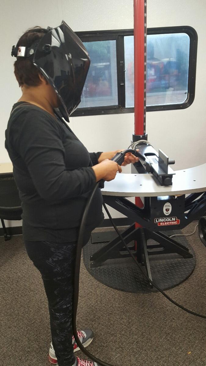A woman tries her hand at a welding simulator.