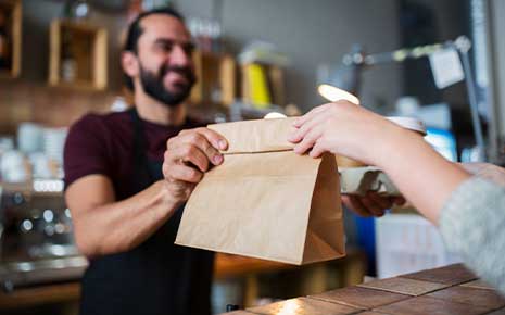 food in paper bag being handed to customer