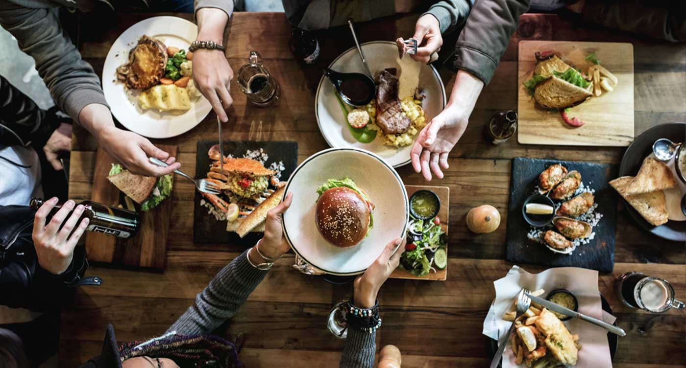 overhead view of restaurant table with friends gathered passing food