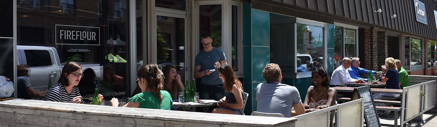 people sitting outside at a downtown restaurant midday